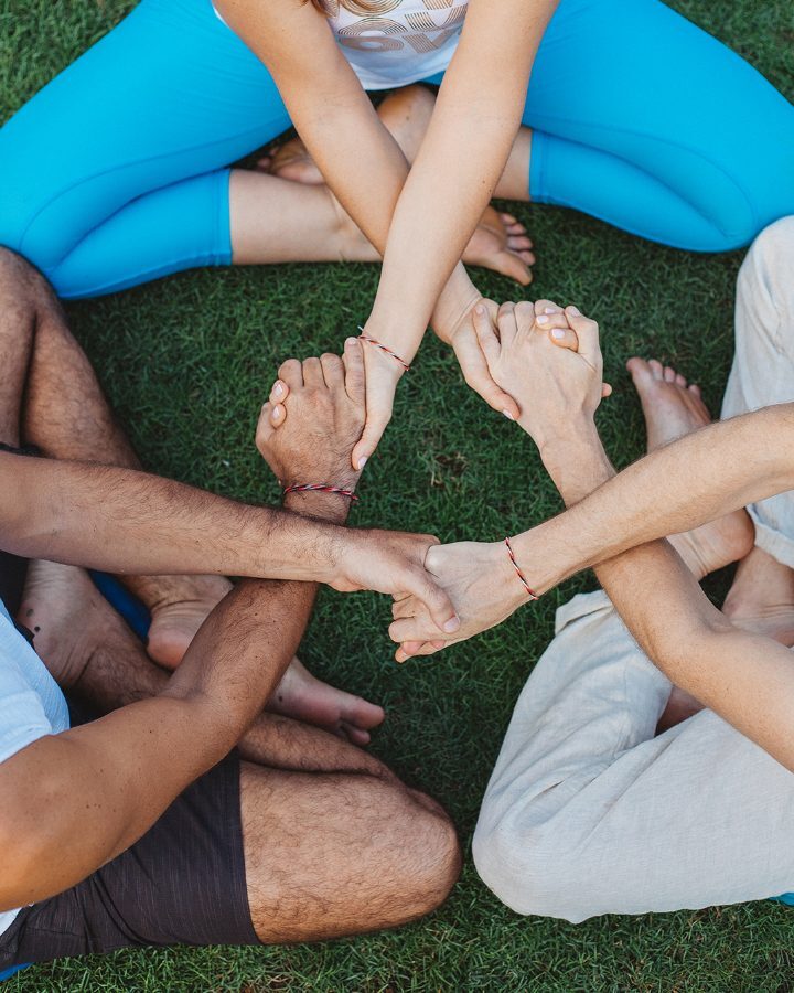 Friends joining hands in a circle on the grass