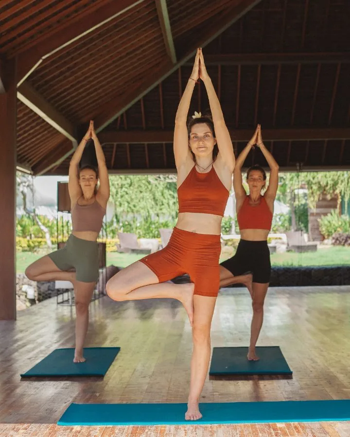 Three students in tree pose in the shala