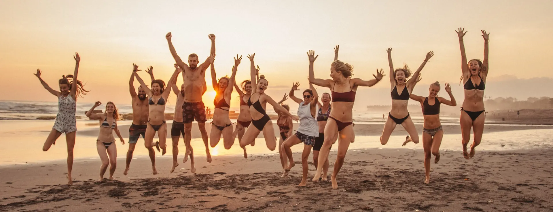 Graduates jumping on the beach at sunset