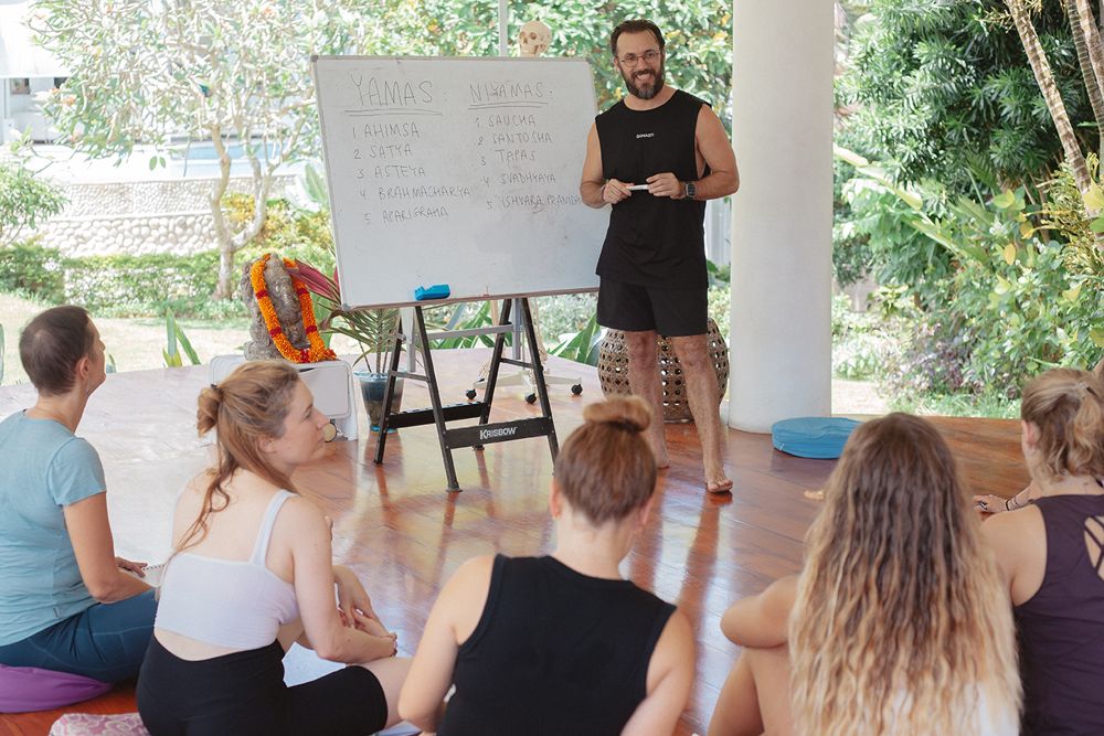 Sean lecturing at a whiteboard to students seated on the floor