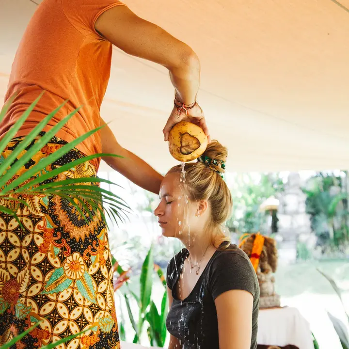 A melukat water blessing, coconut water poured over a student's head