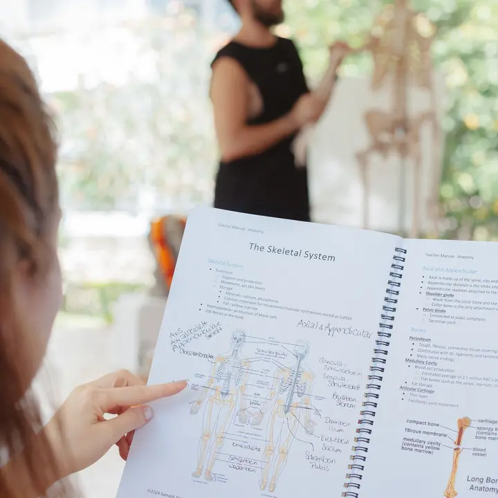 A student following the anatomy manual during a lecture